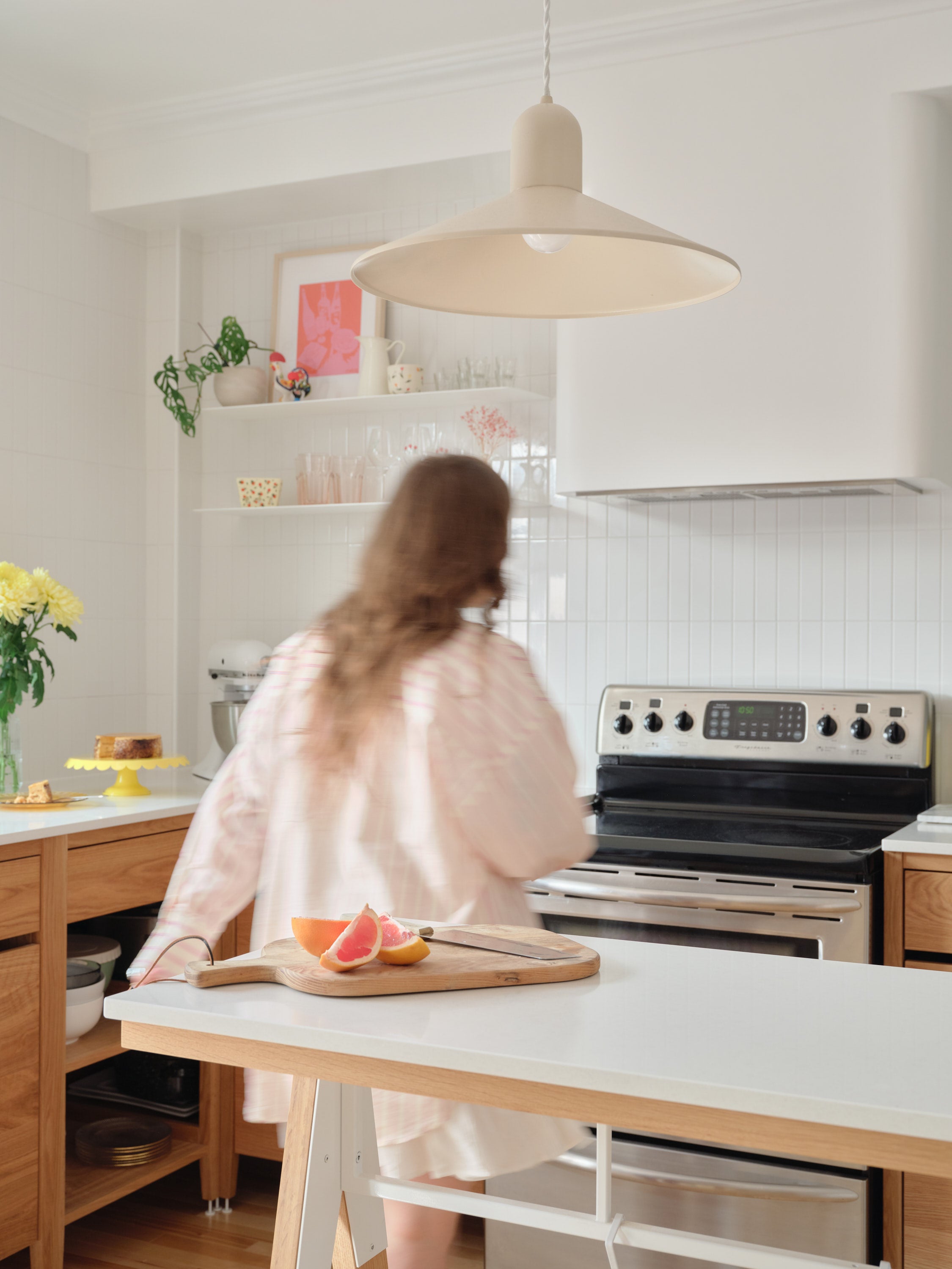 Coquo modular kitchen cabinets in natural oak with white metal feet. The white rectangular backsplash tile, white floating shelves. 