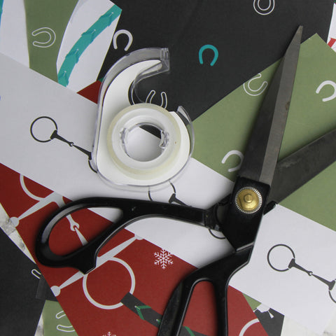 Scraps of equestrian gift wrapping paper with scissors and roll of tape