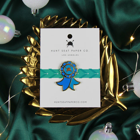 Blue Ribbon winner lapel pin in a gold dish on an emerald green satin background with twinkle lights and christmas ornaments