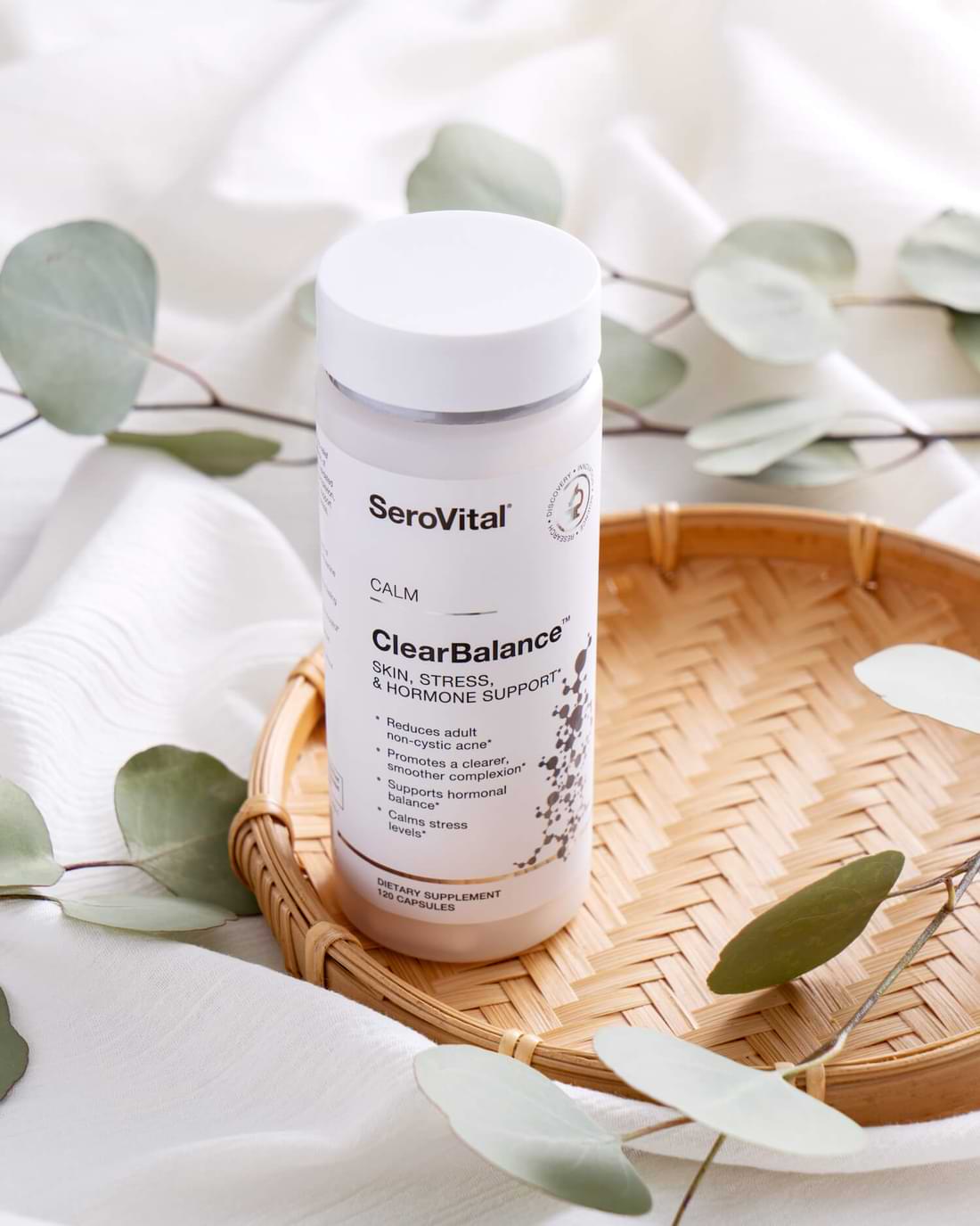A bottle of the supplement ClearBalance on a wicker tray with leaves in the background