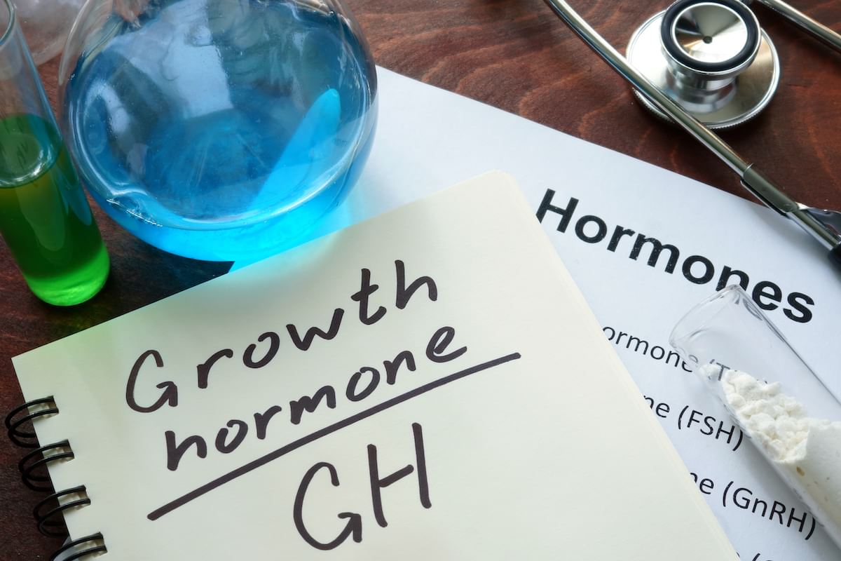 Human growth hormone hand written on notebook with a blue and green test tube nearby