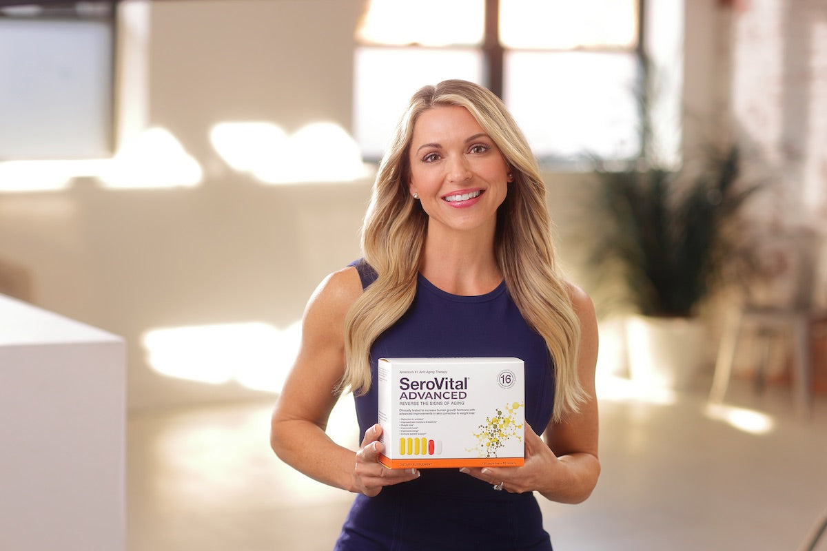Fitness and lifestyle expert Kim Lyons in a dark blue tank top holding a box of SeroVital ADVANCED