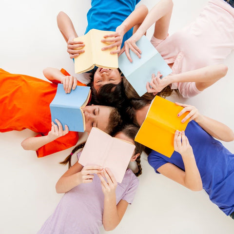 kids laying down in a circle reading colourful books