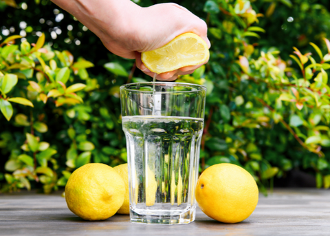 Person squeezing lemon into water