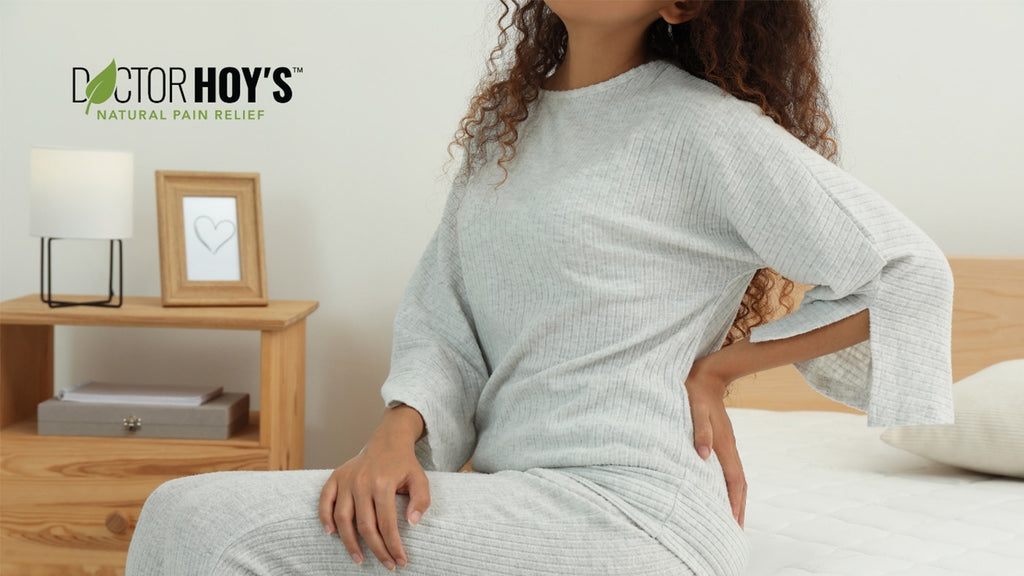 woman with lower back pain sitting on edge of bed