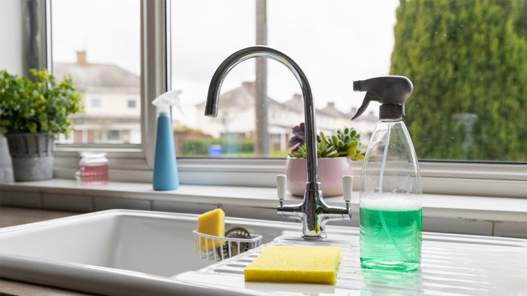 Sink with green spray bottle and yellow sponge