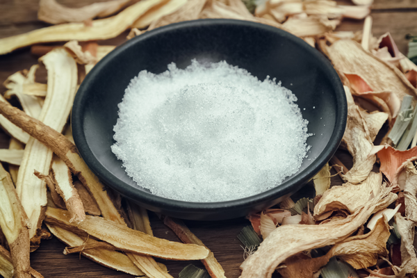 Bowl of crystallized camphor surrounded by pieces of dried camphor