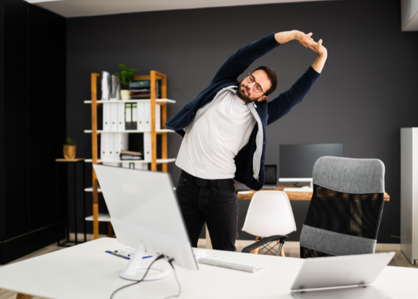 Man stretching while at his work desk