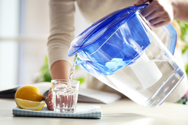 Person pouring water into glass from filtered pitcher