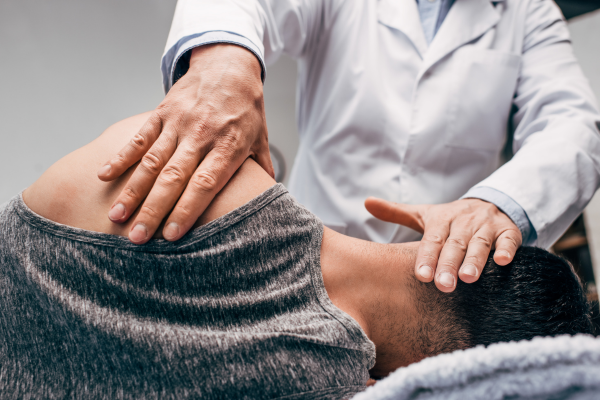 Chiropractor placing hands on a patient’s head and shoulder