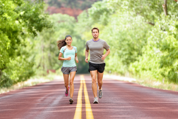 Man and woman with good posture running on track outside