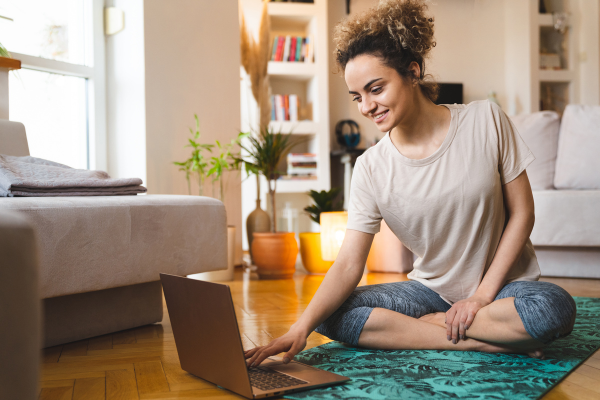 Woman doing yoga at home searching on laptop