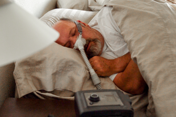 Man wearing sleep apnea machine while asleep in bed