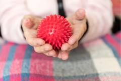 person holding red massage ball