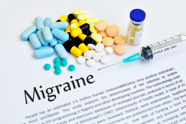 The word Migraine surrounding by pills and a syringe