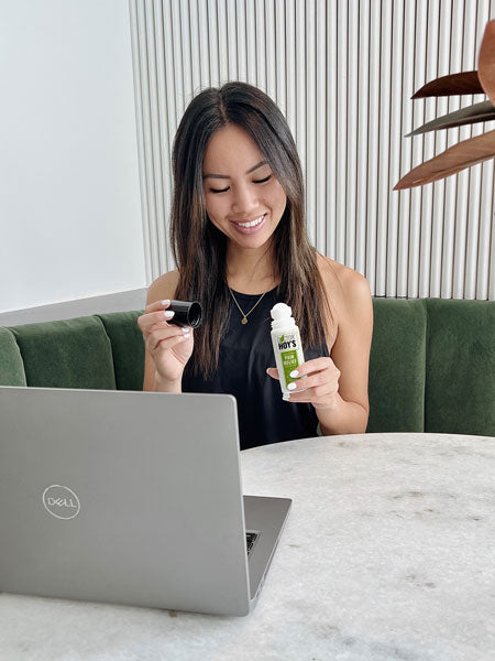  Woman sitting in front of computer while using Doctor Hoy’s roll-on pain relief gel