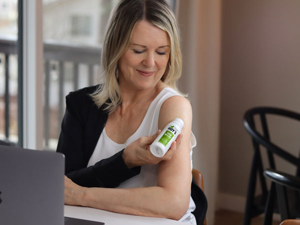 woman applying roll-on topical gel for arthritis to shoulder