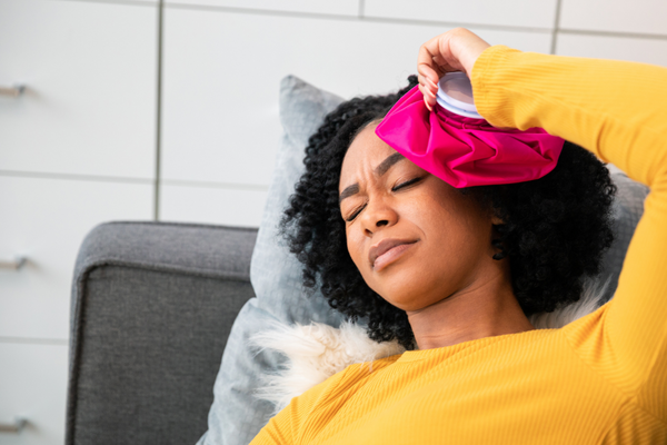 Woman laying down with migraine holding cold compress to head