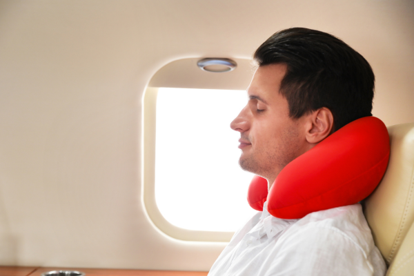 Man sitting on plane with travel neck pillow for postural support