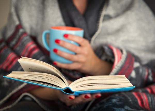 Woman reading a book and holding a cup of tea