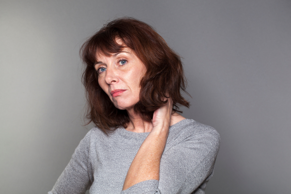 Somber woman with hand placed behind her neck