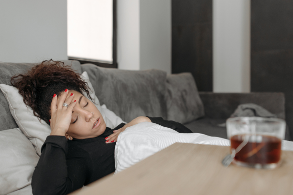 Woman with headache lying on couch asleep