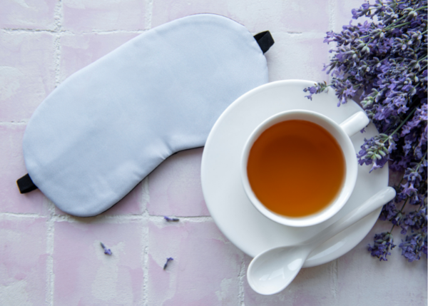 Photo of a sleeping eye mask, chamomile tea, and dried lavender