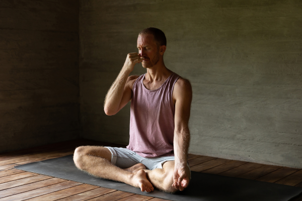 Man performing breathing exercises on yoga mat