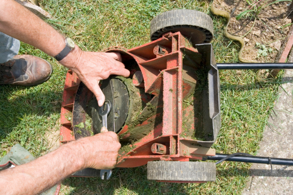 Man using wrench to take apart lawn mower