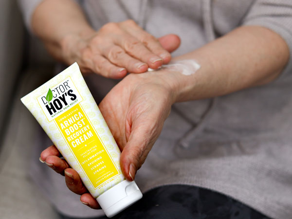 person applying arnica cream to wrist while holding arnica cream tube