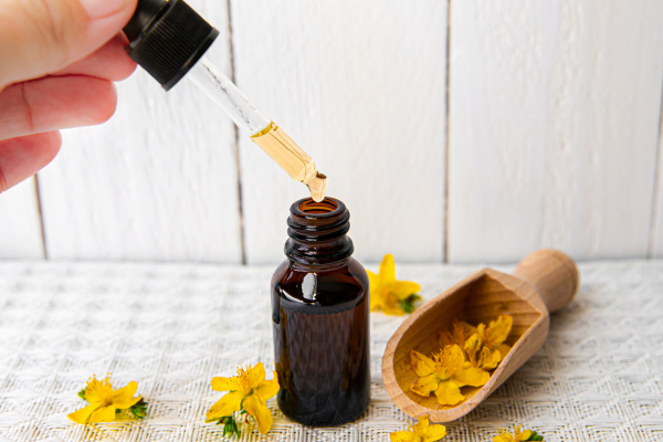 St. John’s wort extract in tincture bottle and wooden shovel with yellow flowers