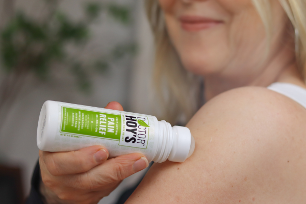 woman applying pain relief gel roll-on to shoulder