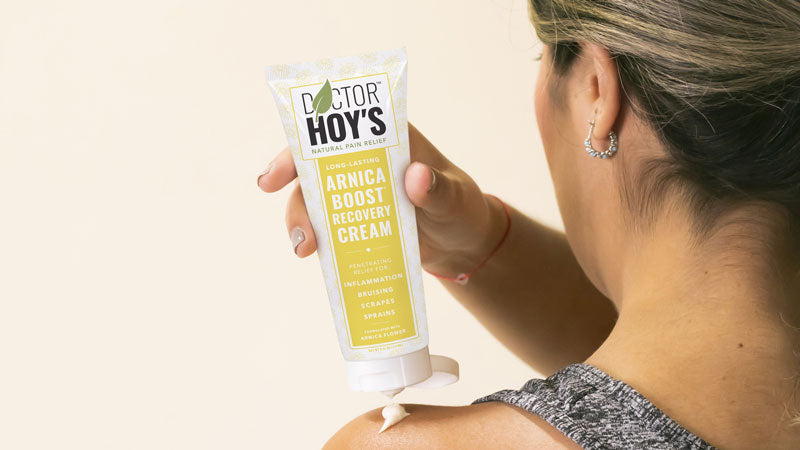 Woman applying Doctor Hoy's Arnica Boost to top of hand to reduce shoulder pain