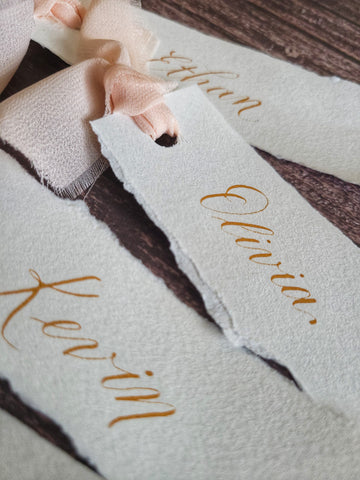Cotton placecards with calligraphy in gold ink and pink ribbon