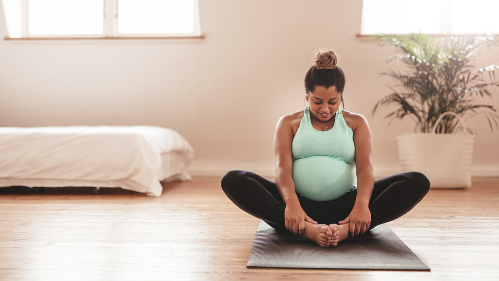 Pregnant woman in bright teal tank top doing yoga