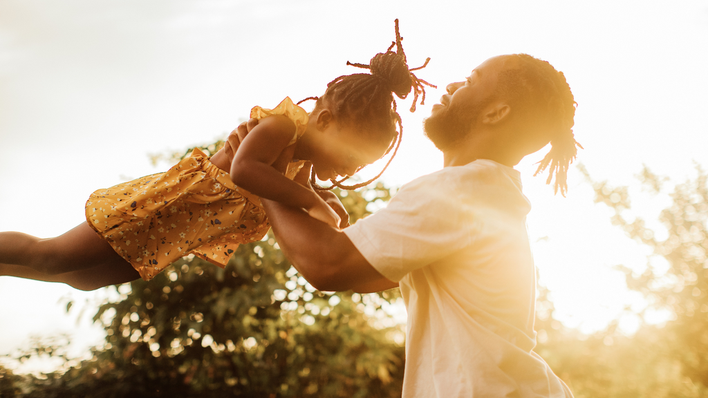 Father playfully swinging his daughter in the air outdoors