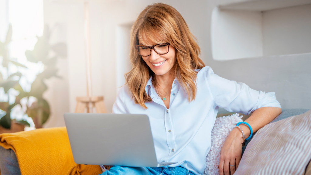 Woman sitting on a couch using her laptop in her lap