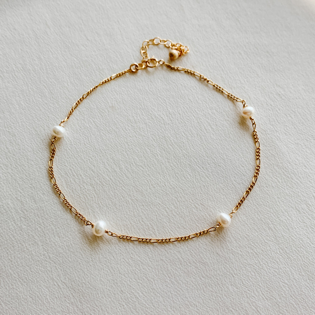 A dainty 14k gold filled anklet featuring four tiny freshwater pearls set in Figaro link chain.