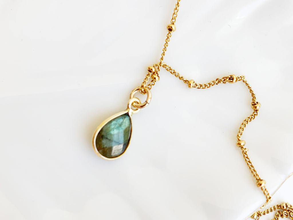 A 14k gold filled beaded chain necklace with a bezel set faceted labradorite pendant in teardrop shape. 