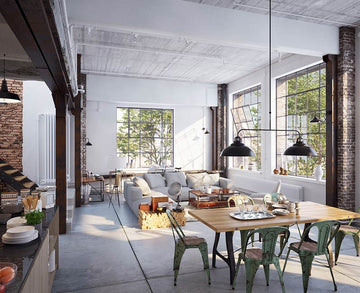 An interior photo of a professionally designed Industrial decor style living room and dining table with an open concept, white and brick walls, large windows, cement floors, a white couch, a wood table, and green metal chairs