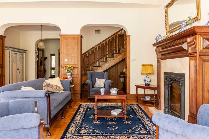 A classic American style home living room with a wood mantel fireplace, a blue rug, and blue furniture