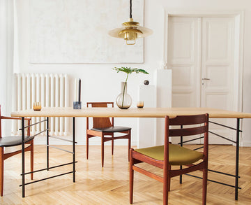 An interior photo of a professionally designed Eclectic decor style dining room with a Modern style chandelier, a Scandinavian style table, Mid-Century Modern styled chairs, and Traditional styled architecture