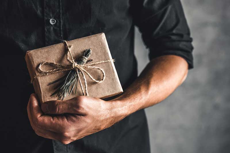 A man holding a brown Christmas present