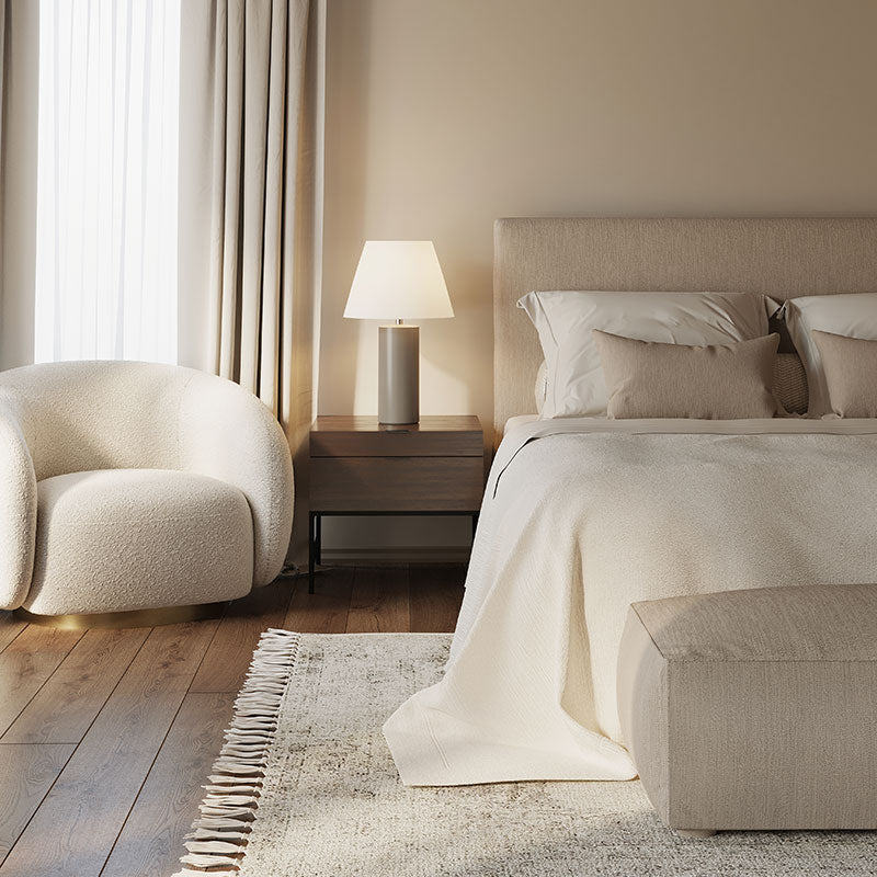 A Cali Casual decor style bedroom with wide plank wood floors, beige walls, a white chair, and beige bedding