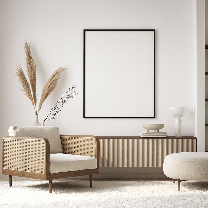 A California Casual decor style living room with white walls, a white area rug, a wood chair with woven rattan and jute sides, and a wood countertop