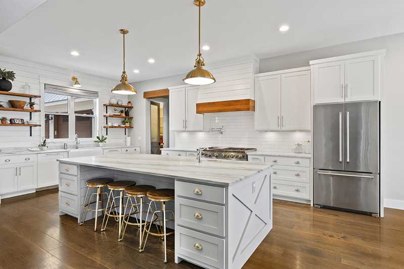 A professionally designed Modern Farmhouse decor style kitchen with white cabinets, shiplap walls, and stained wood floors