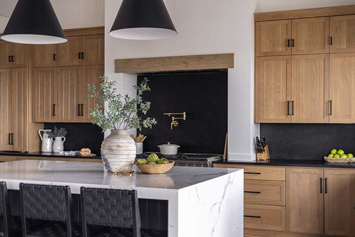 A photo of a Contemporary decor styled kitchen with black walls, marble countertops, wood cabinetry, and brass and black hardware