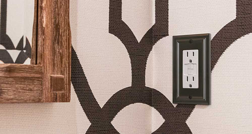 A photo of the Continental oil rubbed bronze wallplate on a woven wallpaper backdrop