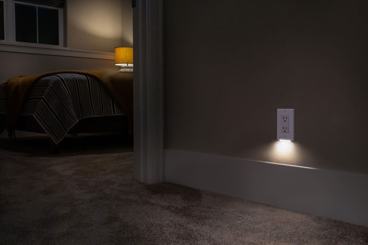 A photo of the classic white decor LumiCover casting light in a hallway at night, with a bedroom in the background