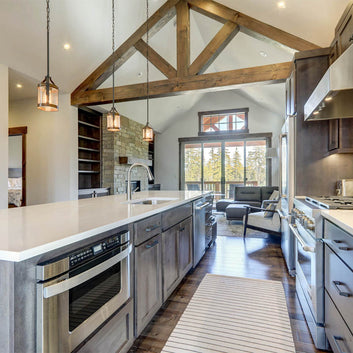 Professionally designed kitchen with a Modern Mountain decor style, large wood exposed beams, large windows, stainless steel appliances, and hardwood floors